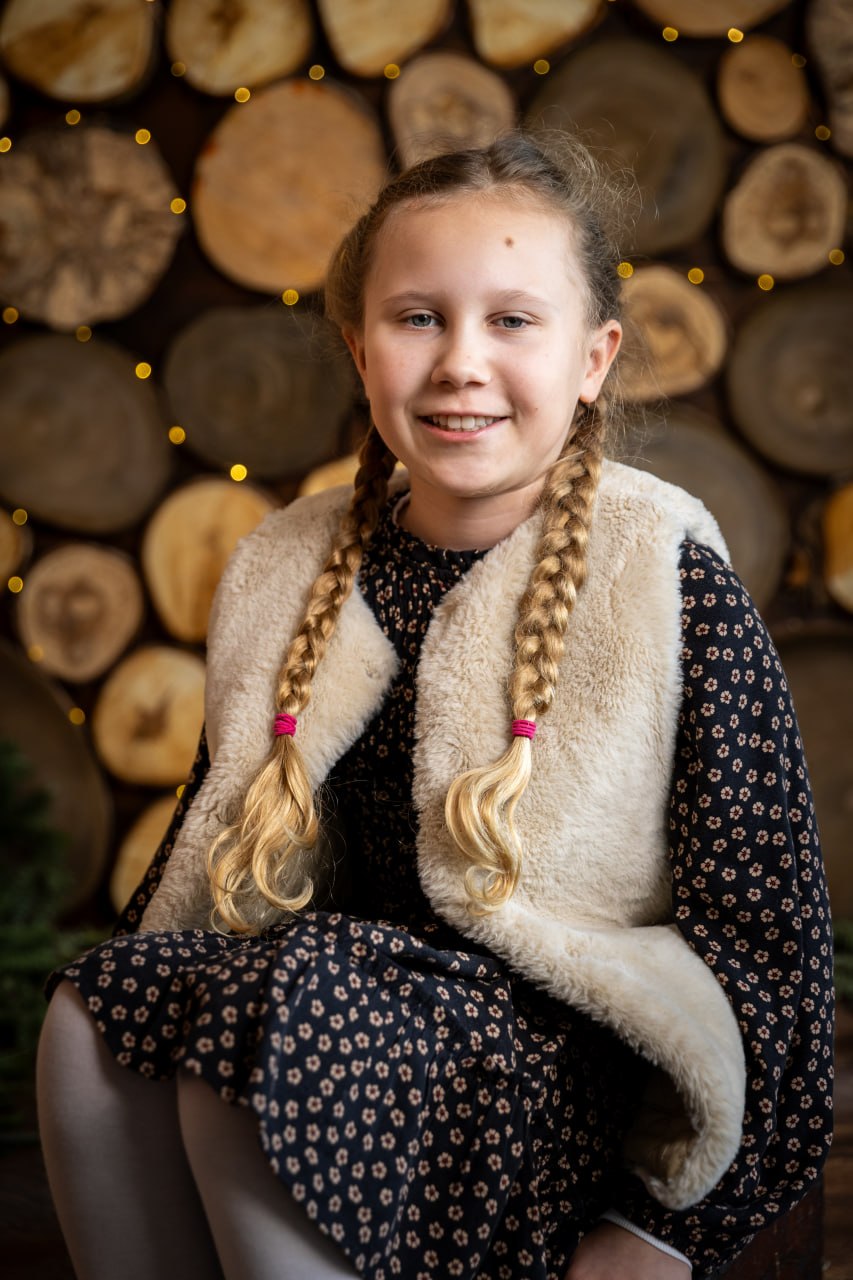 Mädchen im Porträt vor einer Holzwand mit Lichterkette